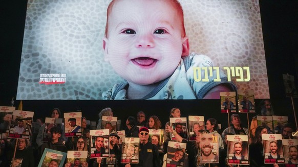 Demonstrators hold portraits of hostages held by Hamas in the Gaza Strip as a video featuring Kfir Bibas, who, along with his parents Shiri and Yarden Bibas, and his brother Ariel, is still being held ...