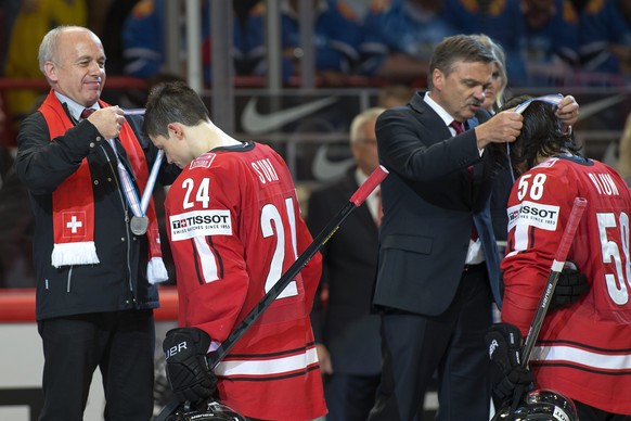 Swiss President Ueli Maurer, left, gives the silver medal to Switzerland&#039;s player Reto Suri, 2nd left, and Rene Fasel, 2nd right, President of the International Ice Hockey Federation (IIHF), to S ...