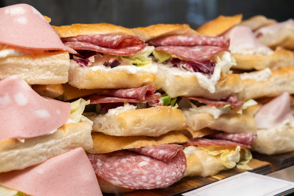 traditional Italian panini sandwich with ciabatta bread with truffle sauce, salami, mortadella sausage, prosciutto and cheese. takeaway, traditional Italian fast food