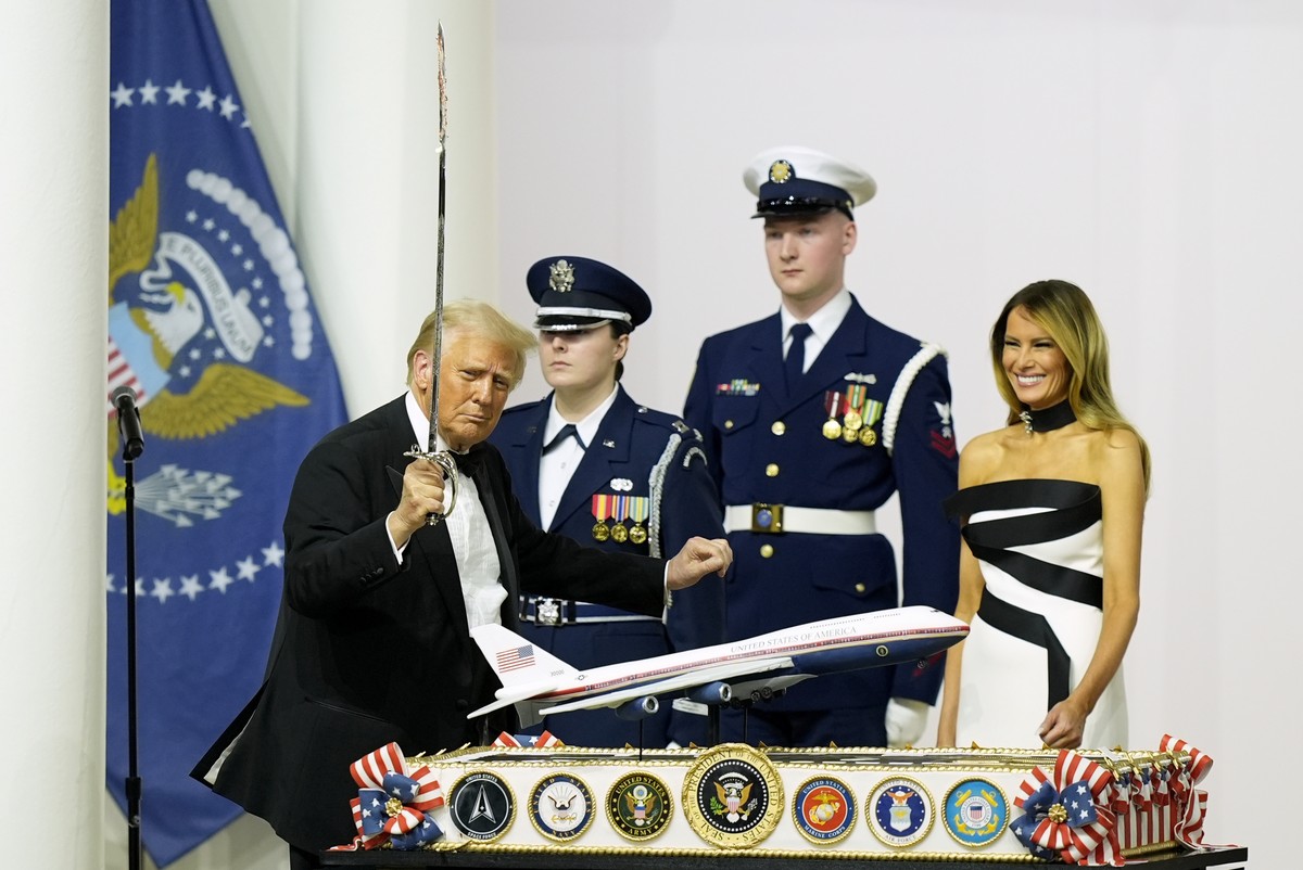 President Donald Trump, left, holds a sabre after using it to cut a cake as first lady Melania Trump, right, watches at the Commander in Chief Ball, Monday, Jan. 20, 2025, in Washington. (AP Photo/Ale ...