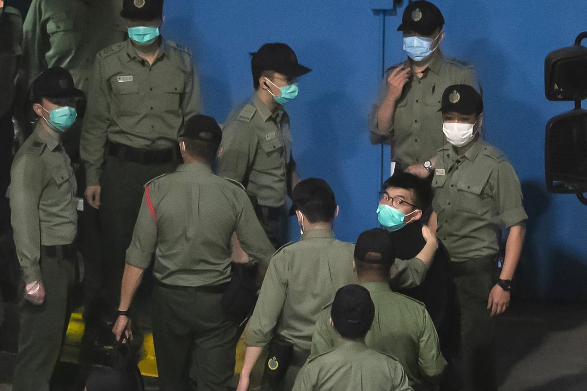 Joshua Wong, right, one of the 47 pro-democracy Hong Kong activists, is escorted by Correctional Services officers to prison in Hong Kong, early Tuesday, March 2, 2021. Hong Kong police on Monday brou ...