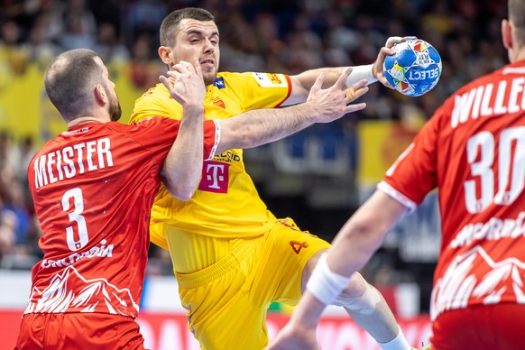 16.01.2024, Berlin: Handball: EM, Nordmazedonien - Schweiz, Vorrunde, Gruppe A, 3. Spieltag, Mercedes-Benz Arena: Martin Velkovski (M) von Nordmazedonien springt gegen die Abwehr von Lucas Meister aus ...