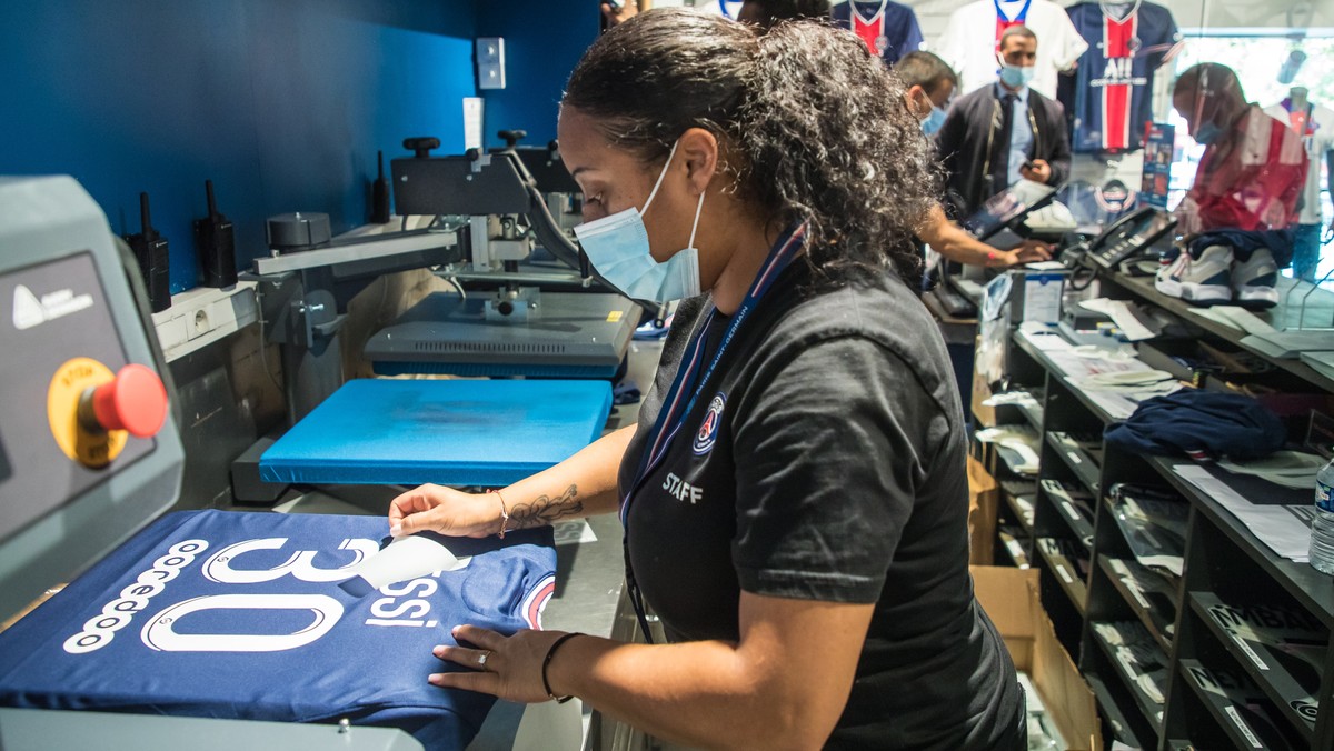 epa09409850 An employee flicks the letters on the new 'Messi 30' jersey at the official Paris Saint-Germain (PSG) store on the Champs Elysee avenue in Paris, France, 11 August 2021. Argentin ...