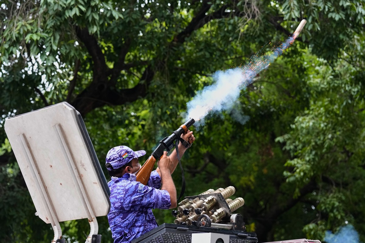 A policeman fires tear gas to disperse supporters of the Cockroach Janta Party as they attempt to march toward India's Parliament, demanding the resignation of the education minister, in New Delh ...