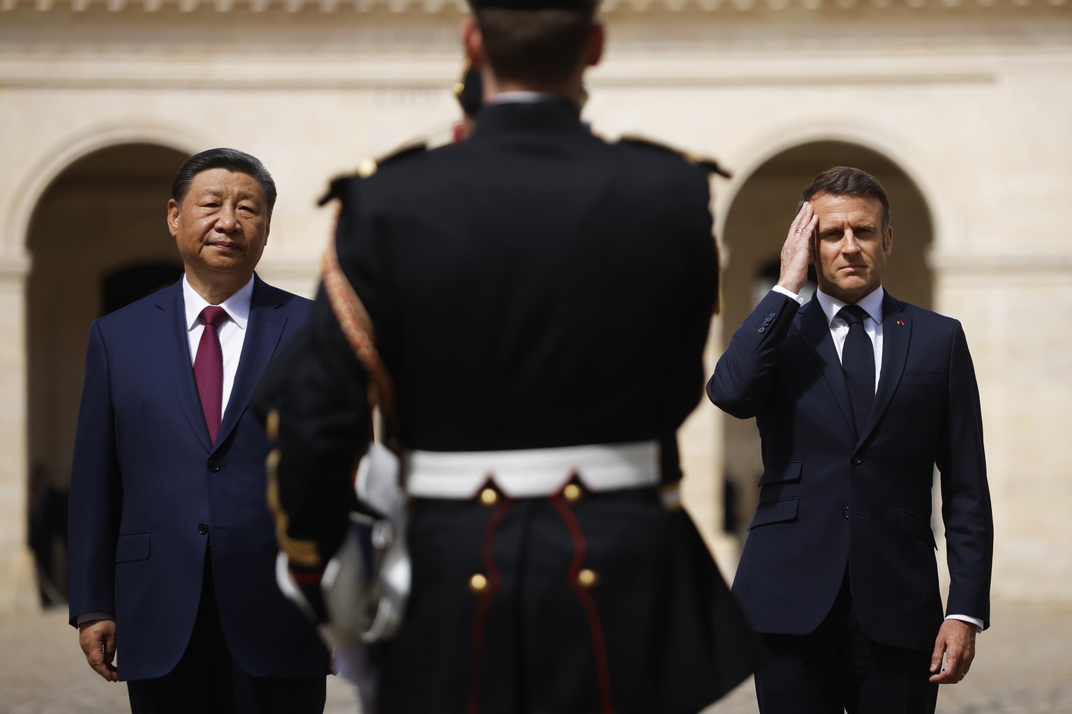 French President Emmanuel Macron and Chinese President Xi Jinping stand in front of the Republican Guards during the official welcoming ceremony at the Hotel national des Invalides in Paris, Monday, M ...