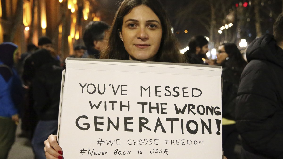 A woman holds a poster during a rally against a draft law aimed at curbing the influence of "foreign agents" near the Georgian parliament building in Tbilisi, Georgia, Thursday, March 9, 202 ...