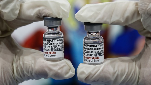 epa10705086 A healthcare worker holds vials of the Pfizer Bivalent COVID-19 vaccine to be administered to fellow healthcare workers at a sports center used as a vaccination facility in San Juan City,  ...