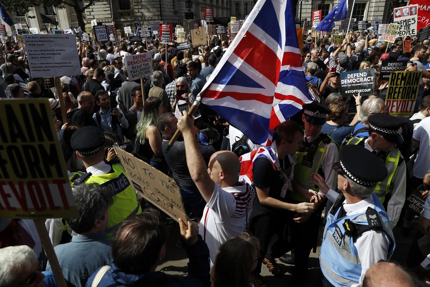 Brexit supporters surrounded by policemen hold British flags as anti Brexit protesters demonstrate during a rally outside Downing Street in London, Saturday, Aug. 31, 2019. Political opposition to Pri ...