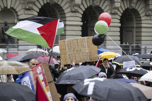 Protesters hold placards and Palestinian flags during a pro-Palestinian rally at the Federal square, in Bern, Switzerland, Saturday Nov. 4, 2023. (Anthony Anex/Keystone via AP)