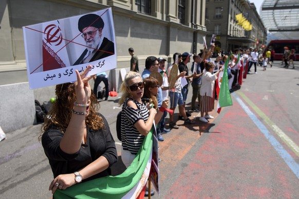 epa06857749 People hold placards and Iranian flags during a protest against the arrival of Iranian President Hassan Rouhani in Bern, Switzerland, 02 July 2018. The Iranian President Hassan Rouhani wil ...