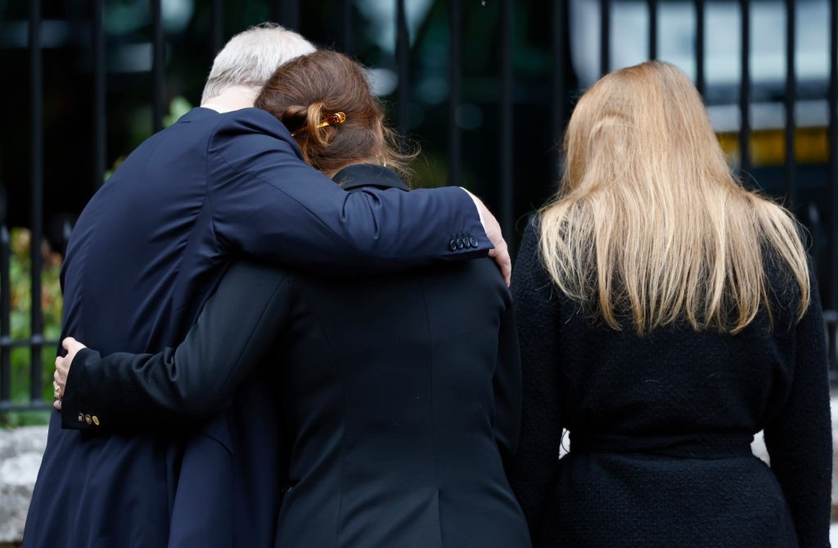CRATHIE, SCOTLAND - SEPTEMBER 10: Prince Andrew, Duke of York puts his arm around Princess Eugenie of York and Princess Beatrice of York as they look at floral tributes outside Crathie Kirk church on  ...