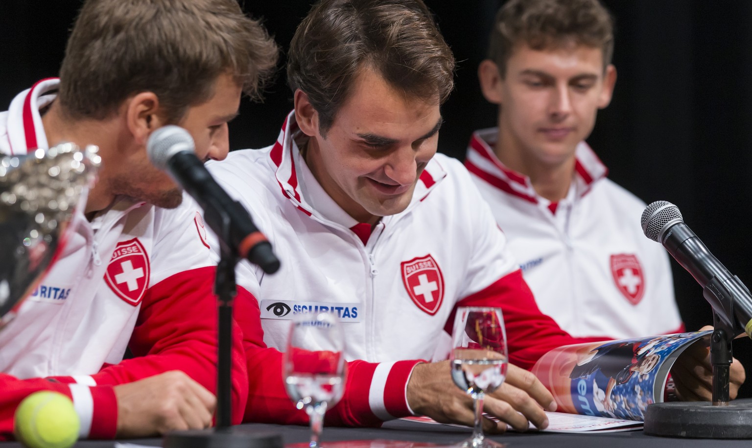 Genf, 17.09.2015, Tennis Davis Cup Schweiz - Holland, Auslosung, vlnr, Marco Chiudinelli, Roger Federer und Henri Laaksonen (SUI) lesen das offizielle Magazin des Davis Cup (Pascal Muller/EQ Images)