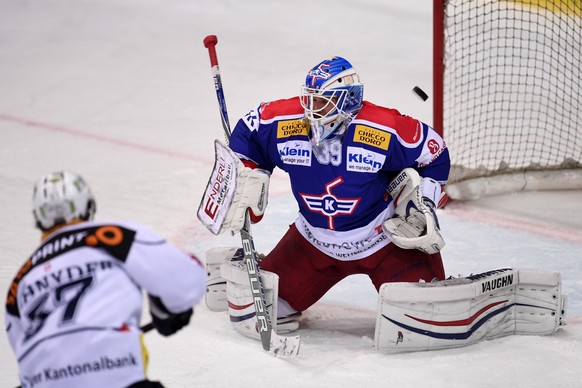 Der Zug Spieler Fabian Schnyder, links, erzielt das Tor zum 3:2 gegen den Kloten Torhueter Luca Boltshauser, rechts, in der Schweizer National League A Partie zwischen dem EHC Kloten und dem EV Zug in ...