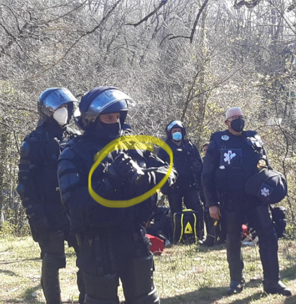 Ein Polizist filmt die Räumung des Mormonthügels mit einer Handkamera.