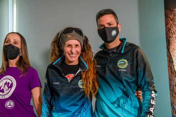epa10572274 Spanish elite athlete, mountaineer and climber Beatriz Flamini (C) poses with assistance coordinator David Reyes (R), after leaving a cave where she remained isolated for 500 days at a dep ...