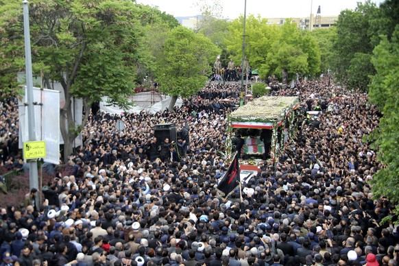 In this photo provided by Fars News Agency, mourners gather around a truck carrying coffins of Iranian President Ebrahim Raisi and his companions who were killed in their helicopter crash on Sunday in ...