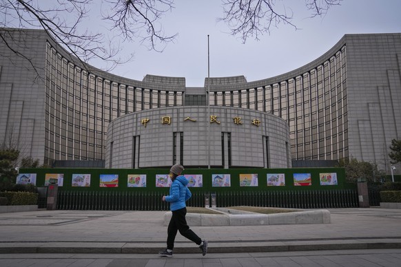 A woman jogs past China&#039;s central bank, or the People&#039;s Bank of China in Beijing, Tuesday, Feb. 20, 2024. China&#039;s central bank announced it cut its five-year loan prime rate while leavi ...
