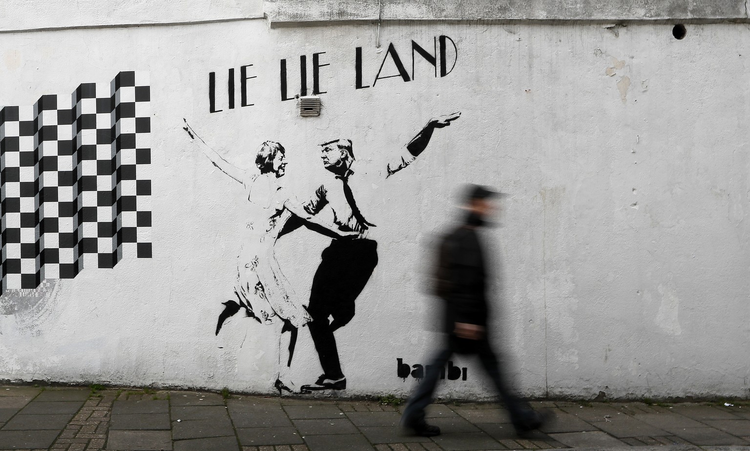 A pedestrian passes a new piece of art by street artist Bambi in London. in London, Thursday, Feb. 16, 2017. The work, entitled Lie Lie Land, features a dancing British Prime Minister Theresa May and  ...