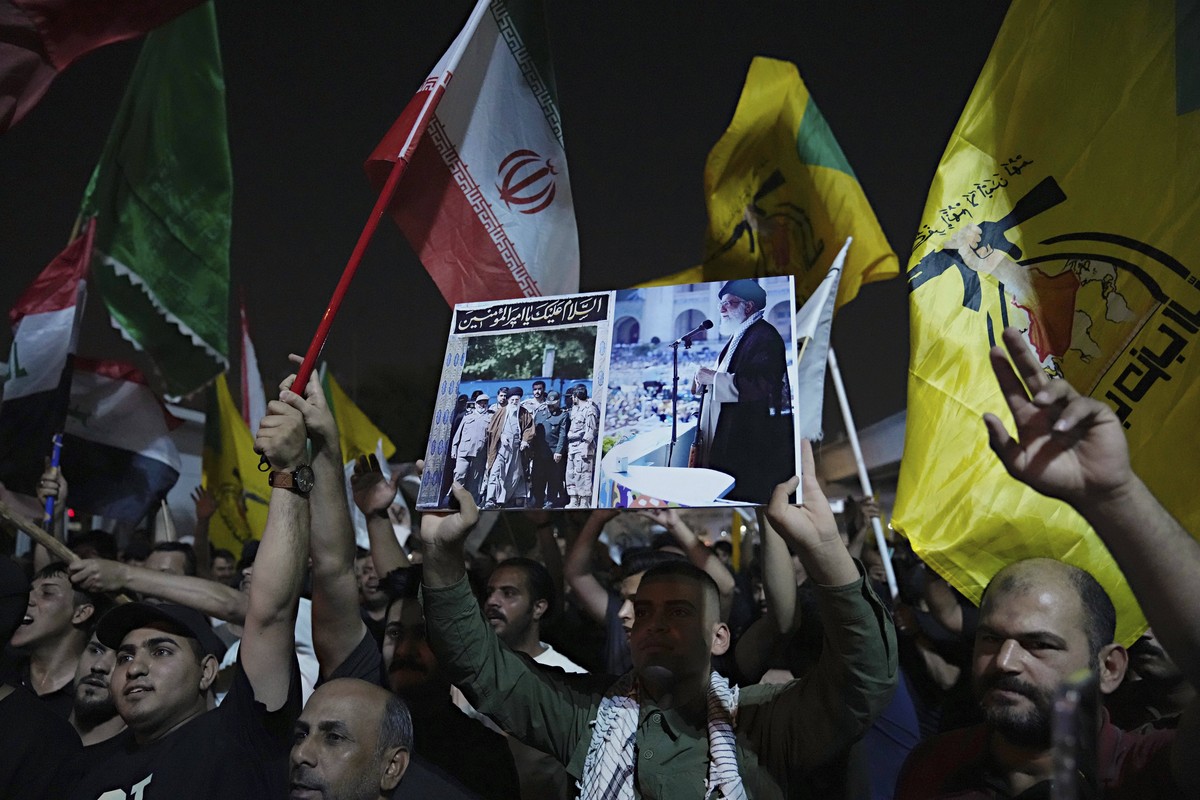 A protester holds a portrait of Iran's Supreme Leader Ayatollah Ali Khamenei during a protest against Israeli attacks on multiple cities across Iran, at a bridge leading to the fortified Green Zo ...