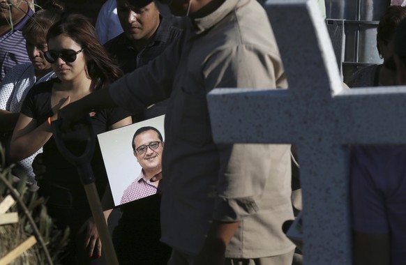 FILE - In this file photo dated Thursday, May 31, 2018, a man carries a portrait of slain journalist Hector Gonzalez Antonio as his daughter, left, mourns during his funeral in Mexico City. Gonzalez,  ...