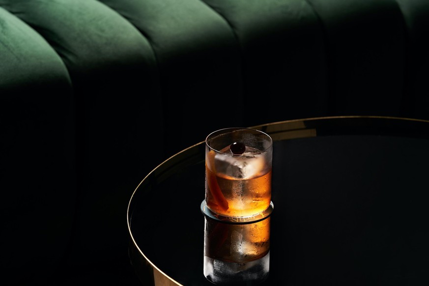 Fresh cocktail glass on glass table in night club restaurant. Alcohol cocktail drink, close-up. Retro alcoholic beverage. Old Fashioned Negroni etc.