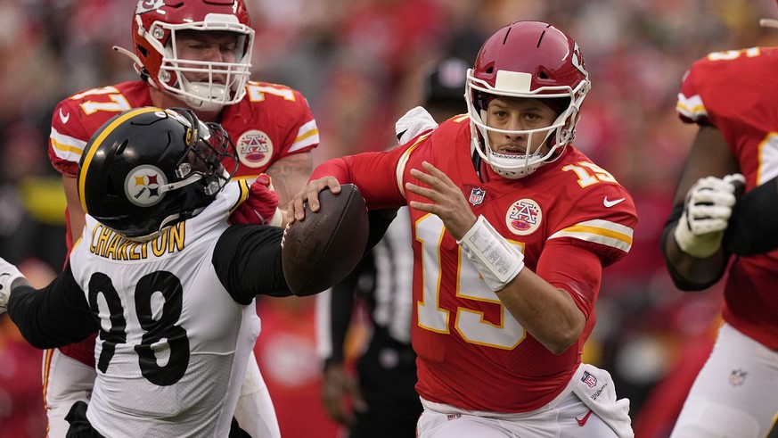 Kansas City Chiefs quarterback Patrick Mahomes, right, slips past Pittsburgh Steelers defensive end Taco Charlton (98) during the first half of an NFL football game Sunday, Dec. 26, 2021, in Kansas Ci ...