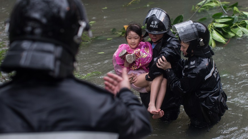 epa07024368 Police officers rescue a child from a flooded street during Typhoon Mangkhut in Lei Yu Mun, Hong Kong, China, 16 September 2018. The No 10 typhoon warning was raised in the early hours as  ...