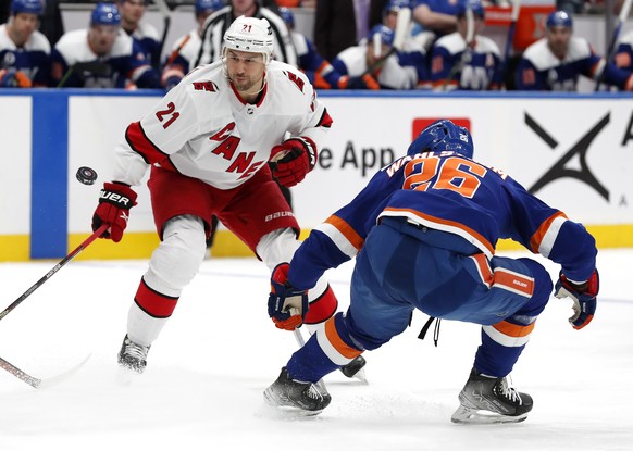 Carolina Hurricanes right wing Nino Niederreiter (21) plays the puck against New York Islanders right wing Oliver Wahlstrom (26) during the first period of an NHL hockey game, Sunday, April 24, 2022, in New York. (AP Photo/Noah K. Murray)