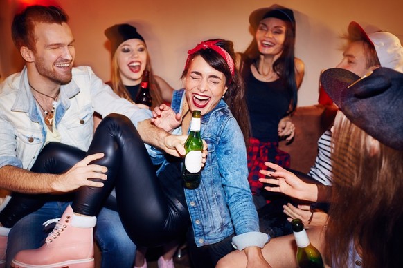 Junge Menschen machen gemeinsam Party und trinken dabei Alkohol.