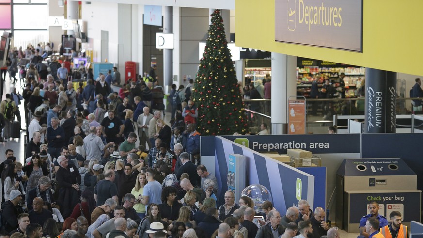People wait near the departures gate at Gatwick airport, near London, as the airport remains closed with incoming flights delayed or diverted to other airports, after drones were spotted over the airf ...