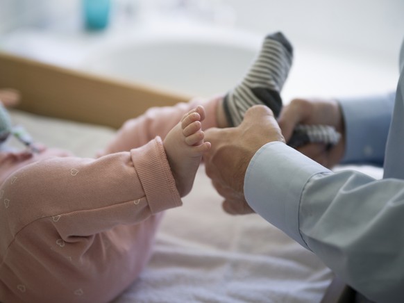 ZUM THEMA VATERSCHAFTSURLAUB STELLEN WIR IHNEN HEUTE, MITTWOCH, 25. OKTOBER 2017, FOLGENDES BILDMATERIAL ZUR VERFUEGUNG --- A father dresses his five-month-old daughter, pictured in Kilchberg, Canton  ...