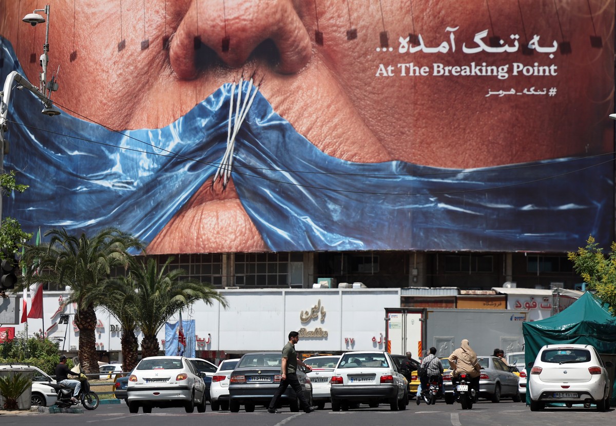 epa12980238 Iranians walk in front of a large anti-US billboard featuring US President Donald Trump and the Strait of Hormuz at Valiasr Square in Tehran, Iran, 21 May 2026. Tensions between the US and ...