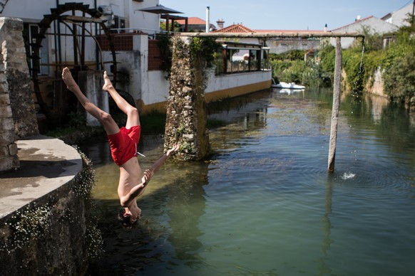 epa06922153 Locals refreshing themselves on Lis river in Leiria, center of Portugal, 01 August 2018. The Portuguese Institute of the Sea and Atmosphere (IPMA), warns that the maximum temperatures will ...