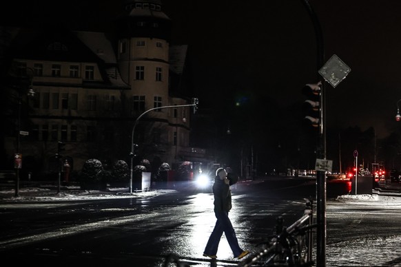 epa12626515 A pedestrian walks on a darkened street in the Zehlendorf district in southwest Berlin, Germany, 04 January 2026. According to state-owned operator Stromnetz Berlin, a large-scale power ou ...
