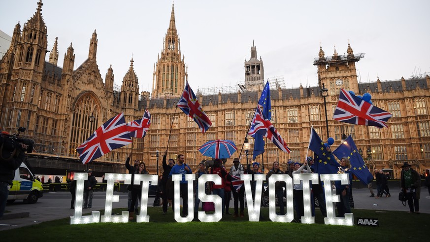 epa07467436 Campaigners asking for a second Brexit referendum stand outisde the Houses of Parliament in London, Britain, 27 March 2019. The British Houses of Parliament are due to hold a number of ind ...