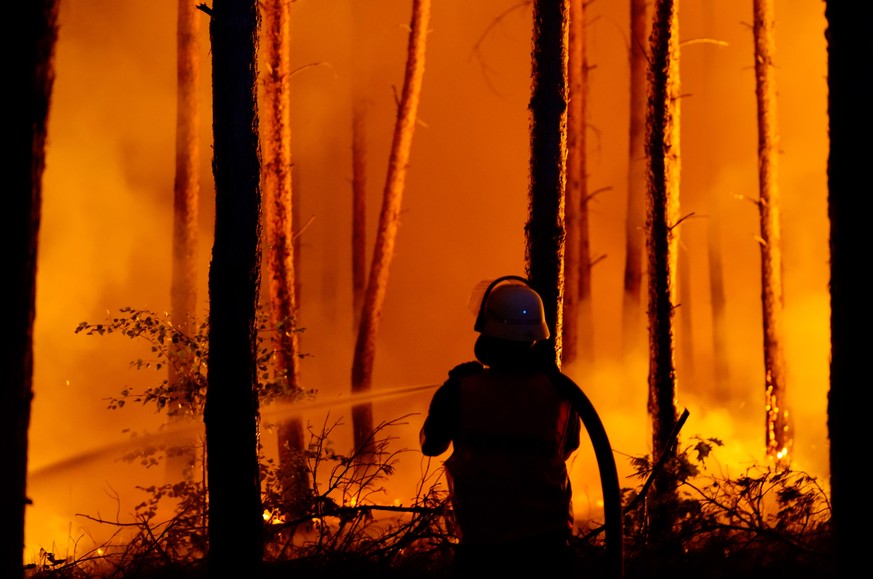 epa06967516 A firefighter in action during a forest fire in Karlsdorf near Treuenbrietzen in South Brandenburg, Germany, 23 August 2018. Due to a forest fire three villages in Brandenburg, Frohnsdorf, ...