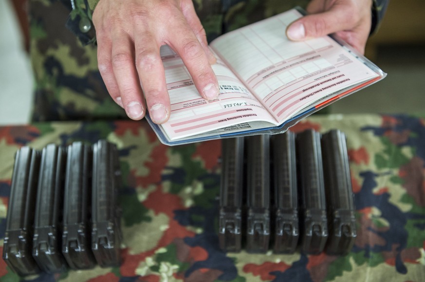 Ein Armeeangehoeriger kontrolliert das Dienstbuechlein, im Hintergrund Waffen Magazine, wahrend der Abgabe des Sturmgewehrs waehrend der Entlassungsinspektion in der Kaserne Rappischtal in Birmensdorf ...