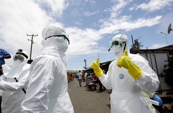 epa04448159 A Liberian Red Cross burial team gears up to collect a suspected Ebola victim in the impoverished area of West Point, Monrovia, Liberia, 15 October 2014. Latest statistics from the United  ...