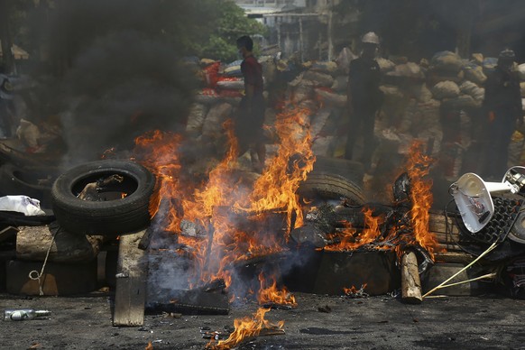 Anti-coup protesters are seen behind their makeshift barricade that protesters burn to make defense line during a demonstration in Yangon, Myanmar, Sunday, March 28, 2021. Protesters in Myanmar return ...