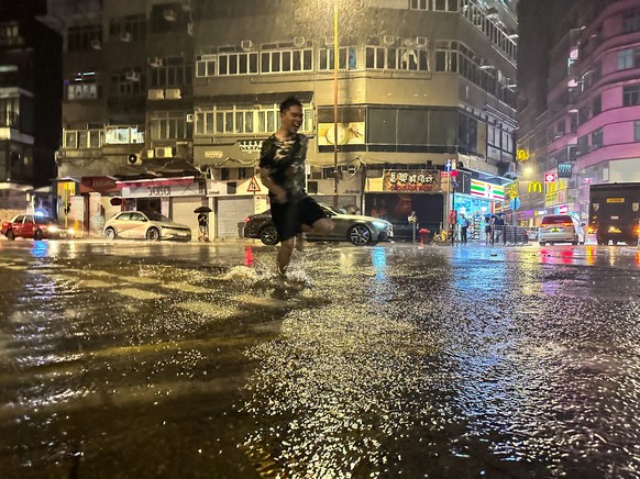 epa10847278 A man runs along a flooded street, as persistent torrential rains batter the city after a recent typhoon, in Hong Kong, China, September 8, 2023. The government has stopped…