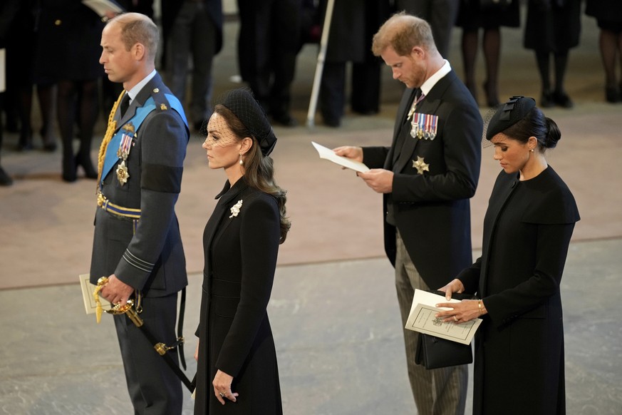 Britain&#039;s Prince William, left, Kate, Princess of Wales, second left, Prince Harry, and his wife Meghan, the Duchess of Sussex, right, pay their respects to Queen Elizabeth II as the coffin rests ...