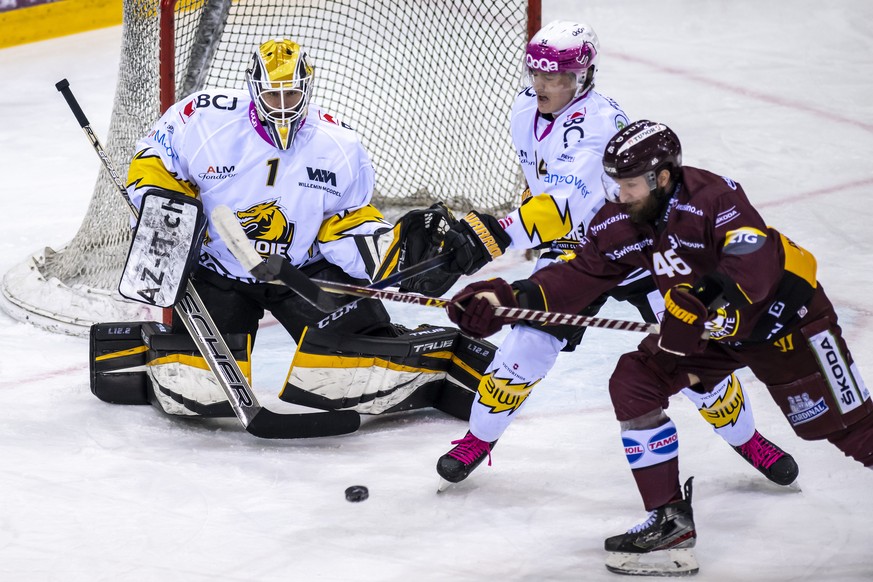 Le defenseur jurassien Dario Bartholet, centre, a la lutte pour le puck avec l&#039;attaquant genevois Benjamin Antonietti, droite, devant le gardien jurassien Tim Wolf, gauche, lors du match du champ ...