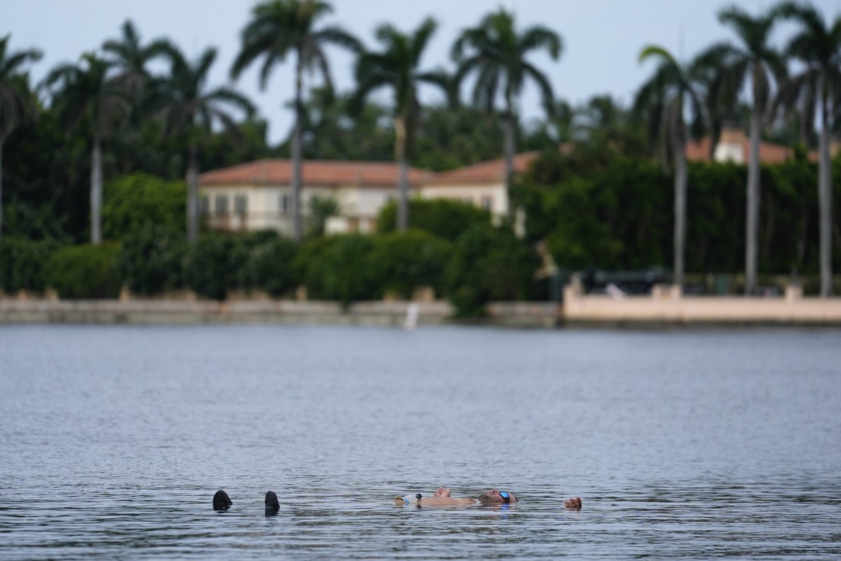 Trump supporter Jestin Nevarez, of Lake Worth, Fla., cools off with a swim in the Lake Worth Lagoon in front of the Mar-a-Lago estate of Republican presidential nominee and former President Donald Tru ...