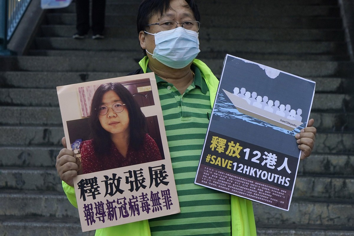 A pro-democracy activist holds placards with the picture of Chinese citizen journalist Zhang Zhan outside the Chinese central government's liaison office, in Hong Kong, Monday, Dec. 28, 2020. Zha ...