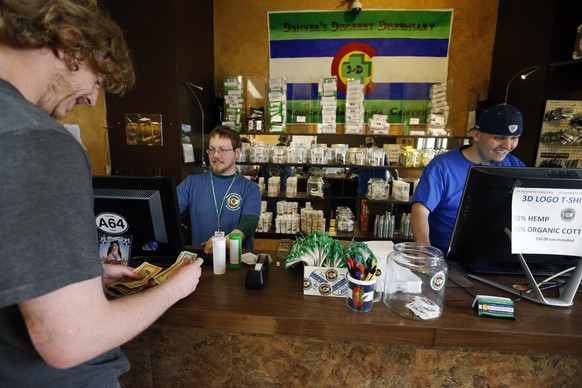 A customer pays cash for retail marijuana at 3D Cannabis Center, in Denver, Thursday, May 8, 2014. Frustrated by the cash-heavy aspect of its new marijuana industry, Colorado is trying a long-shot bid ...