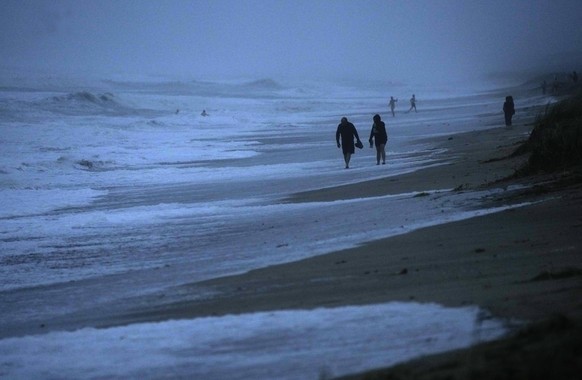 People walk along the oceanfront at Jensen Beach Park, where waves were reaching the dune's edge as conditions deteriorated with the approach of Hurricane Nicole, Wednesday, Nov. 9, 2022, in Jensen Be ...