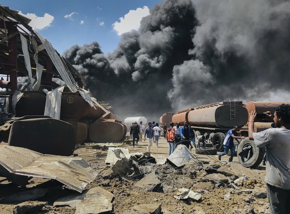 FILE - People are seen in front of clouds of black smoke from fires in the aftermath at the scene of an airstrike in Mekele, the capital of the Tigray region of northern Ethiopia on Oct. 20, 2021. The ...