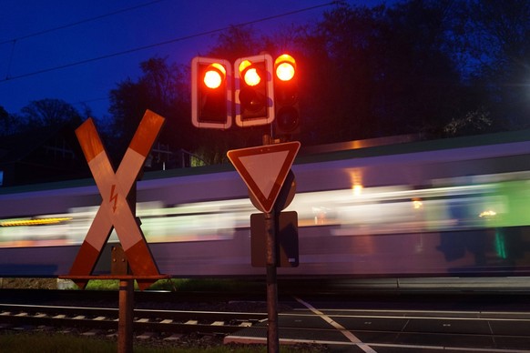 S-Bahn und Individualverkehr Ein Zug überquert einen geschlossenen und durch Schranken und roten Ampeln gesicherten Bahnübergang während auf der Straße der Individualverkehr unterwegs ist. *** S-Bahn  ...