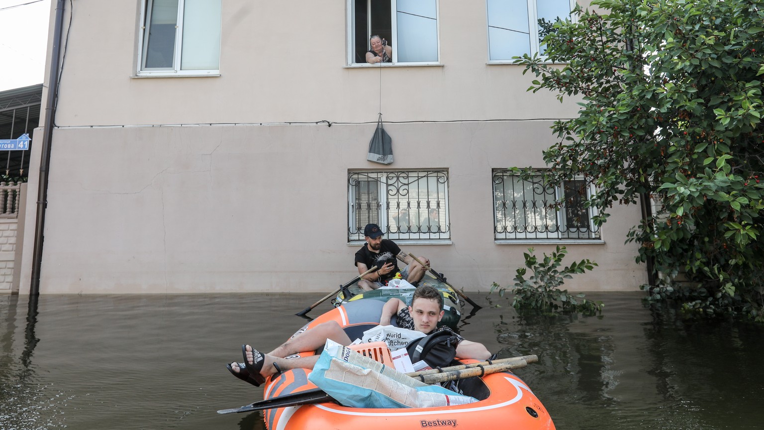 epa10681878 Volunteers deliver food to a local residents in a flooded area of Kherson, Ukraine, 09 June 2023. Ukraine has accused Russian forces of destroying a critical dam and hydroelectric power pl ...