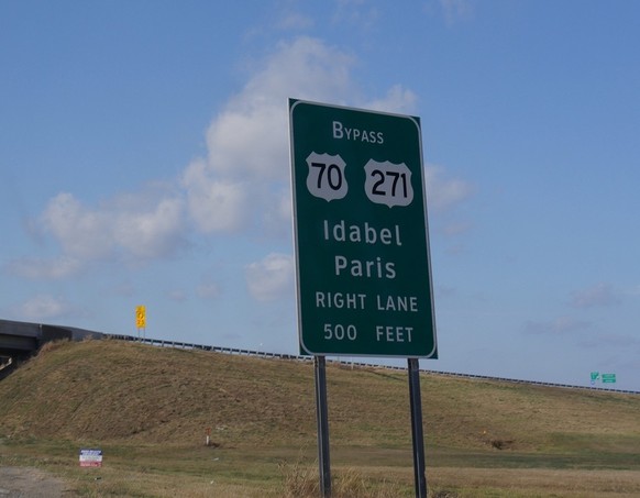 Ein Strassenschild/Wegweiser, welches den Weg nach Paris (Texas) anzeigt.